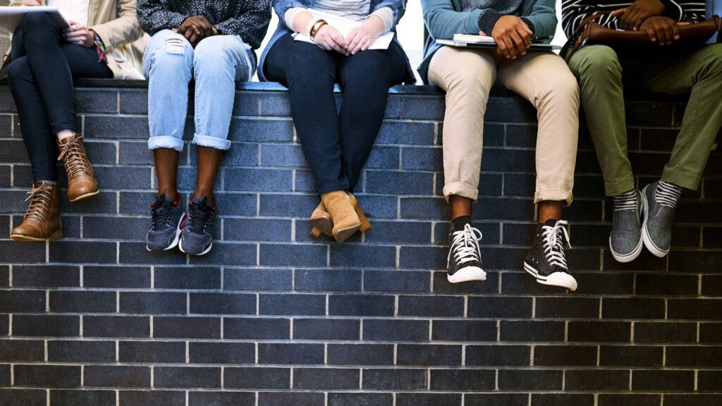 student legs hanging off brick wall
